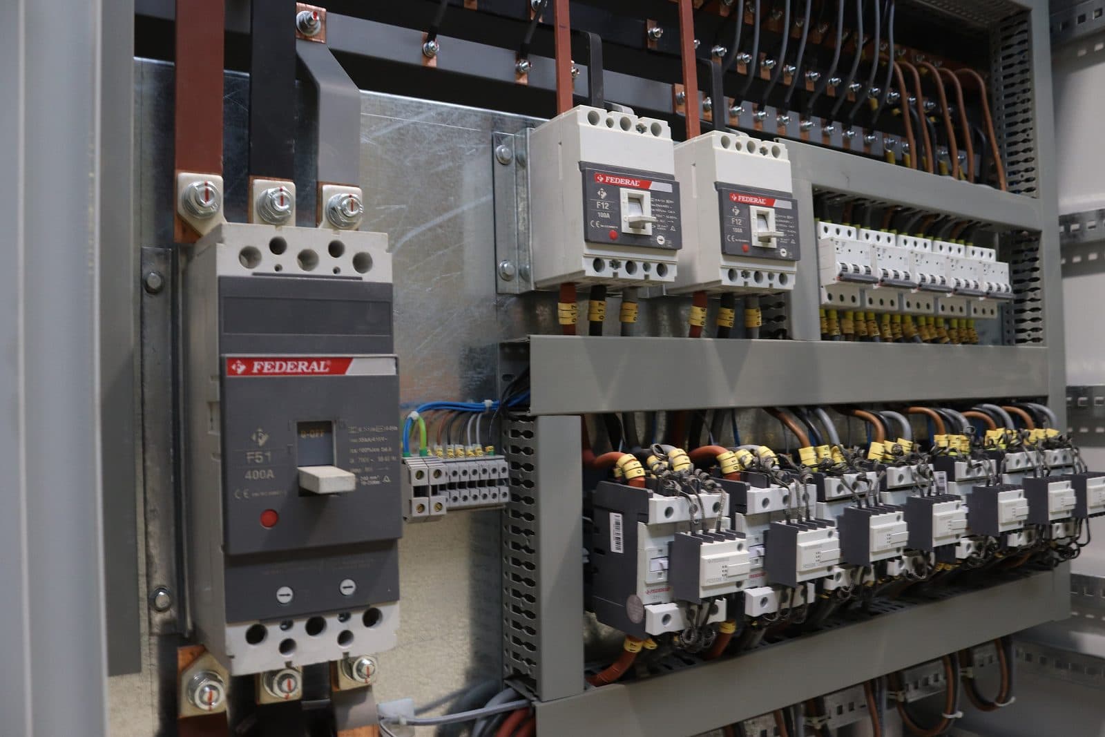 Interior de un tablero: interruptor principal, contactores, borneras y cableado peinado sobre la placa de montaje